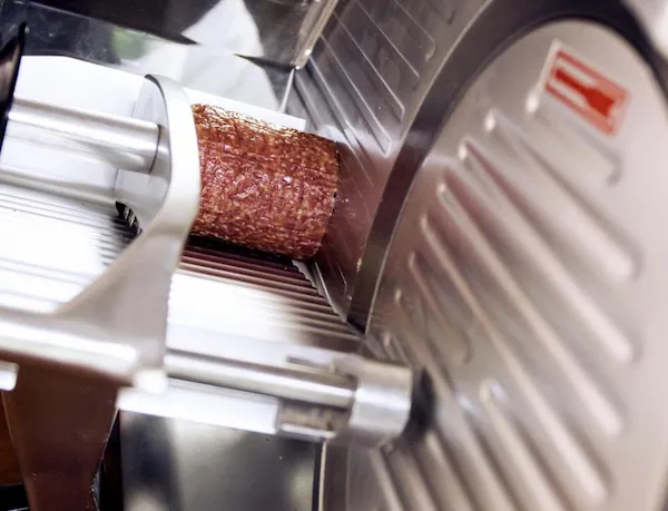 Rebanadora de precisión en acero inoxidable cortando salame